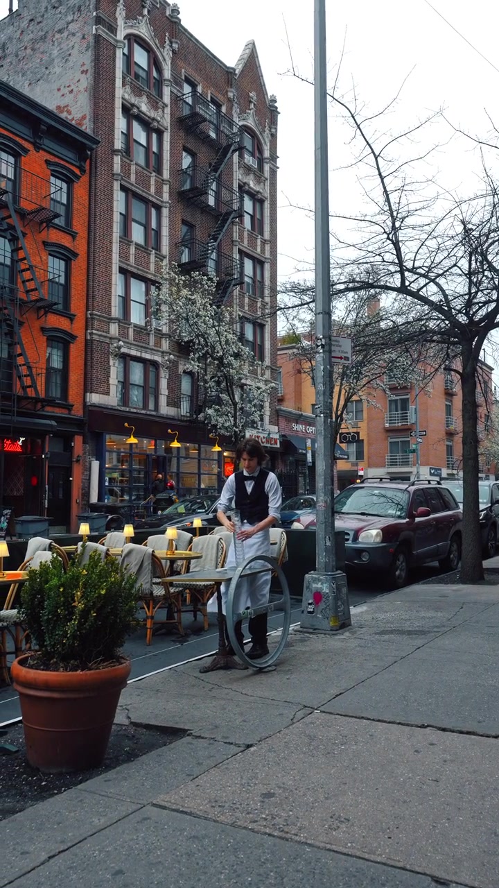 New York, USA, 1 maj 2026: Servitör dukar upp utomhusrestaurangbord på New York-gata. Servitör i förkläde arrangerar bistrobord på trottoarrestaurang.