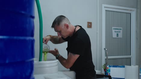 man pouring liquid into a large container