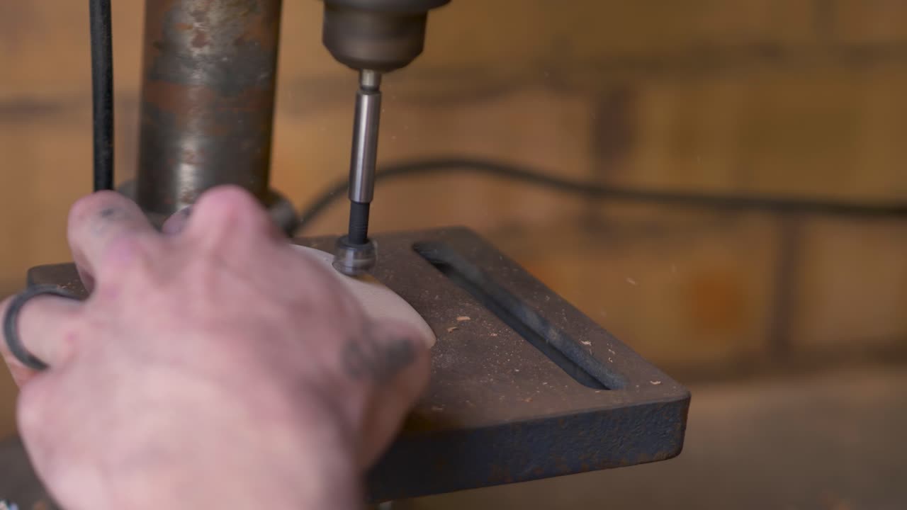 Slow motion close-up of hand holding still with drill piece tool twisting into wooden indoor climbing holds with dust particles spraying at home DIY workshop machinery in Australia industry carpentry