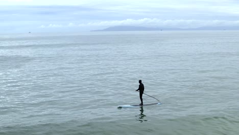 aerial view above single paddle boarder riding peaceful ocean waves off ventura beach, california