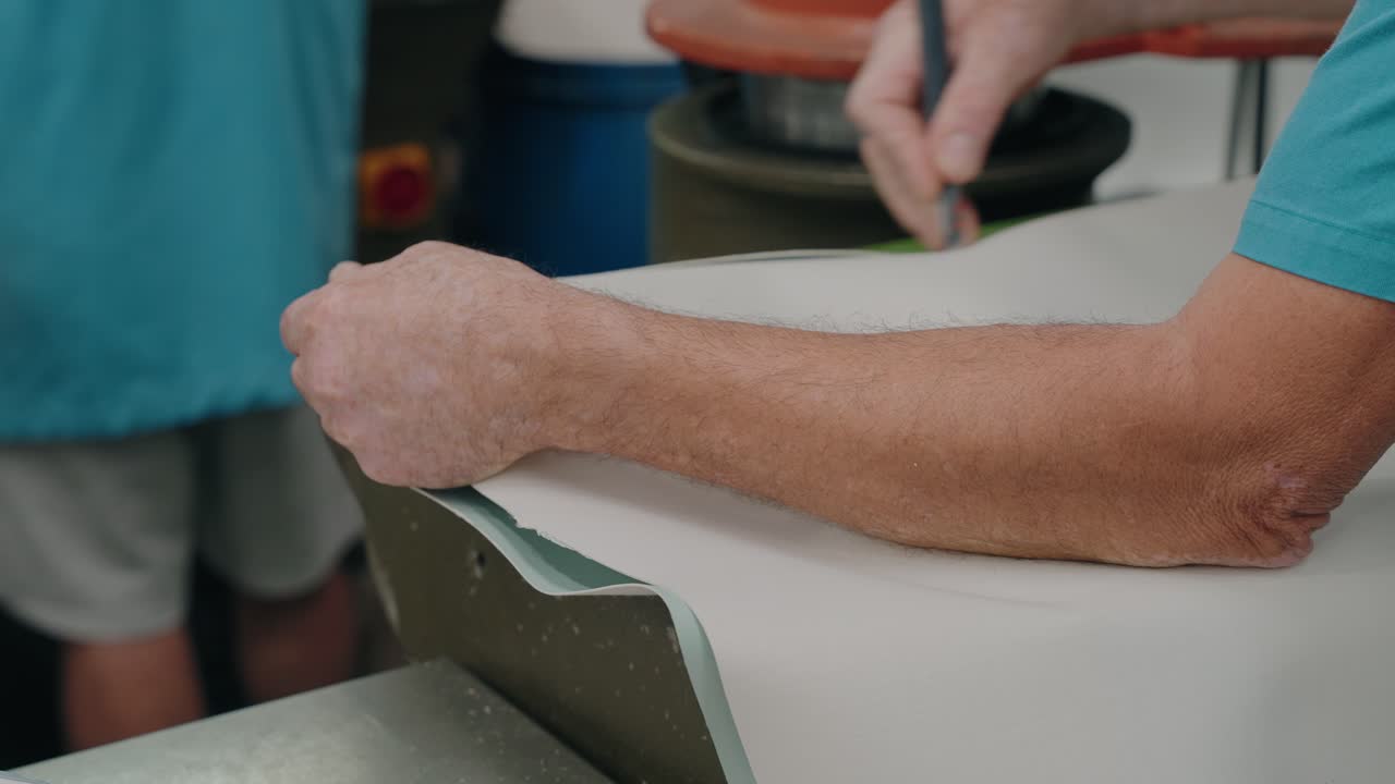 신발 제작 시 가죽 시트를 자르기 전에 손으로 가죽 시트를 조정하는 모습