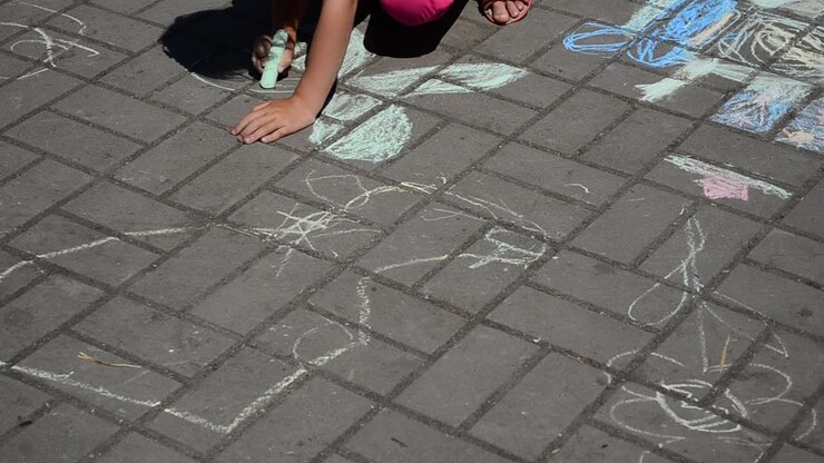 Children draws chalk. Shooting in the summer
