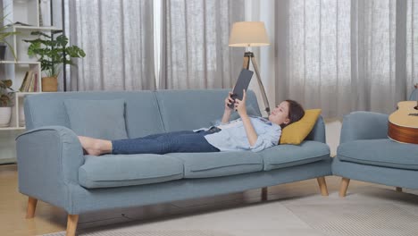 teenage girl relaxing on couch with tablet