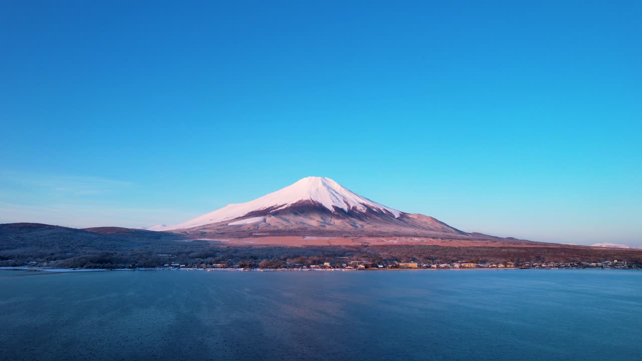 drone volando hacia el nevado monte fuji y una pequeña ciudad japonesa