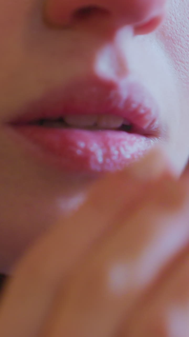 Close-up of woman bringing elegant hands to mouth, exhaling warm breath to stay warm in cold winter night, visible breath vapor emphasizes cold atmosphere, with festive blurred golden lights