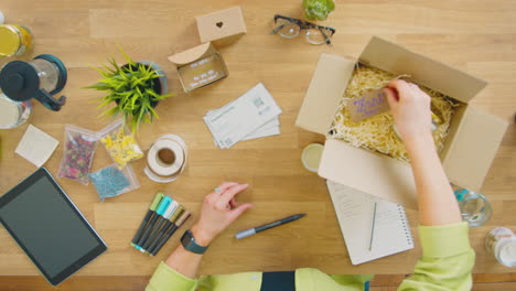 overhead shot of woman running online business making candles packaging them for dispatch