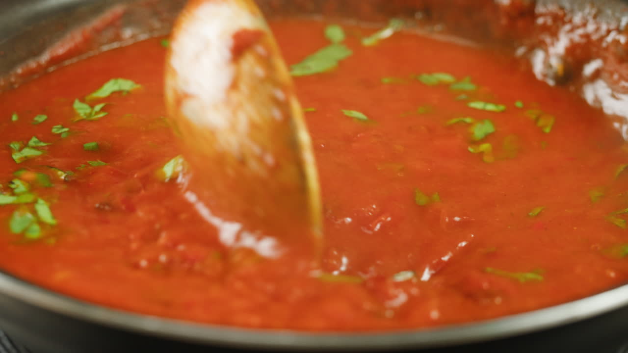 Chicken in tomato sauce is boiling on a frying pan with spices. Cooking tomato sauce curry with chicken fillet. Traditional Italian Mexican Asian dish. High quality studio shot for cafe, restaurant close up.