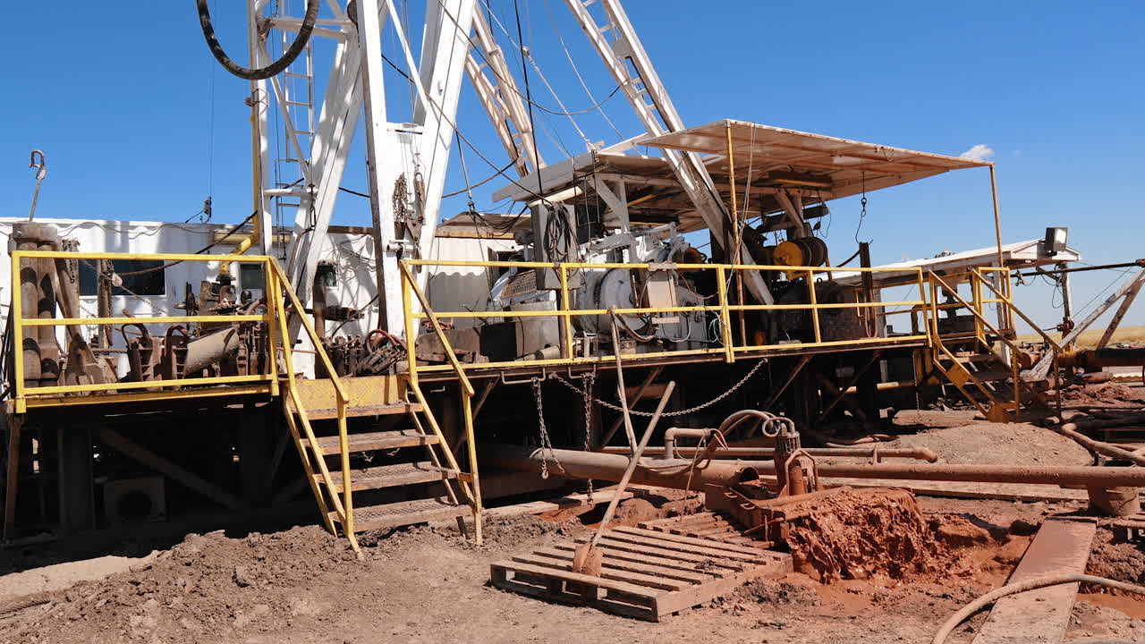 Drilling site with necessary equipment for oil or gas production in the deserted area. Dirty water colored orange flows from the pipe.