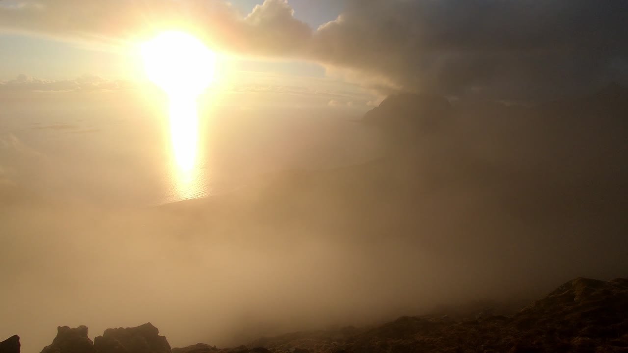 Fog rolls over mountains above Utakleiv during midnight sun timelapse from Mannen in Lofoten