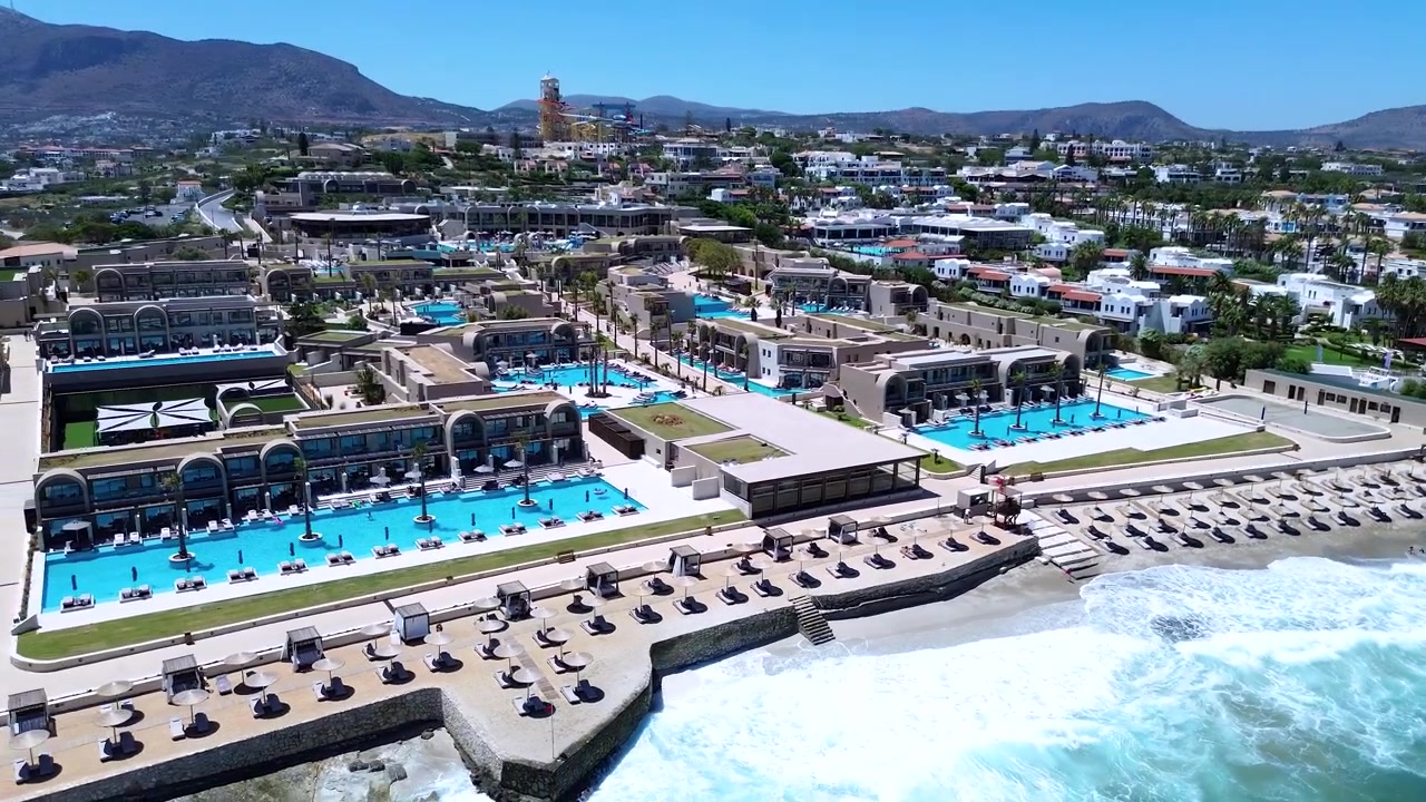 Moderne piscine di resort turistici e lettini prendisole sul lungomare vicino a Hersonissos, Grecia, ripresa aerea orbitante.