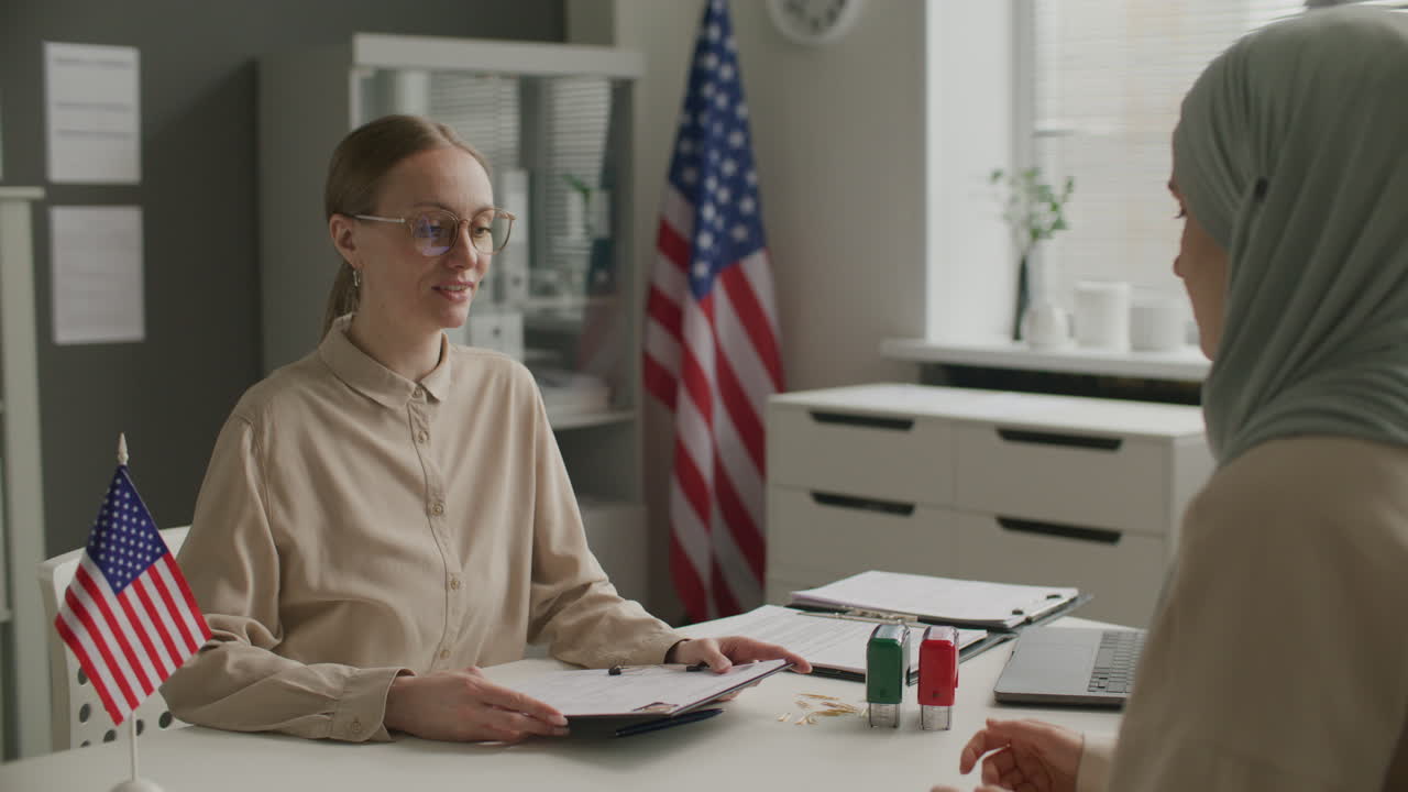 Female Visa Officer Shaking Hands with Muslim Woman after Successful Interview