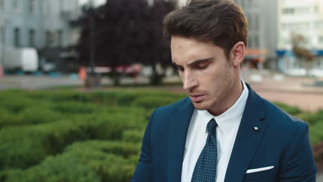 Portrait-of-serious-business-man-reviewing-documents-in-city-walk.-Man-in-park