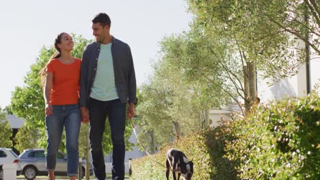 una feliz pareja caucásica está llevando a su perro a pasear