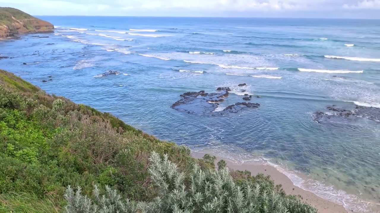 オーストラリアのモーニントン半島で、岩だらけの海岸の崖に打ち寄せる波を上空から見た様子