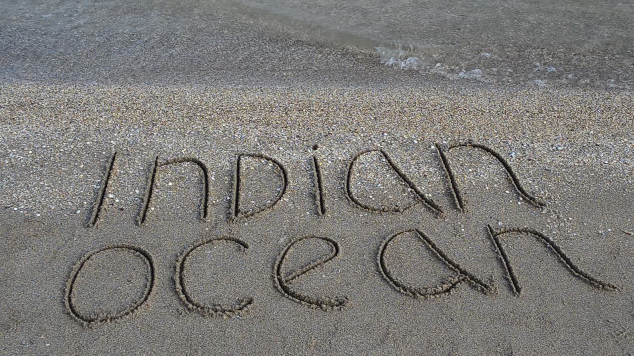 Inscription the Indian Ocean on sand on the beach. Shooting on the beach