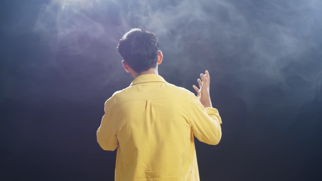 백색 연기 검은 배경에 마이크를 들고 노래하는 어린 소년의 뒷면