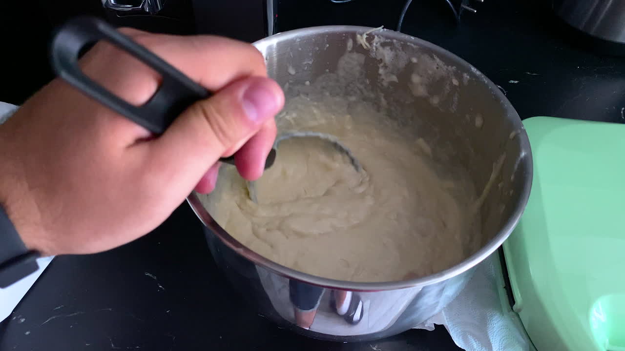 Man mixing his left hand the cake for savoury pancakes, homemade pancakes with sausage and cheese, slow motion