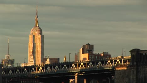 the empire state building rises above the surrounding buildings and freeway in the foreground