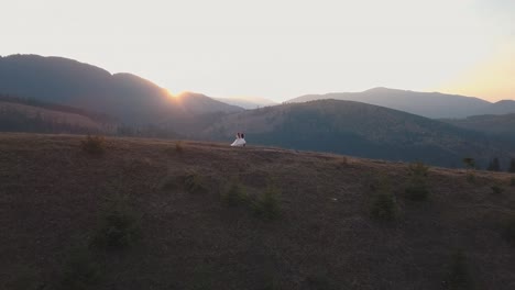 Newlyweds-running-on-a-high-slope-of-the-mountain.-Groom-and-bride.-Aerial-view