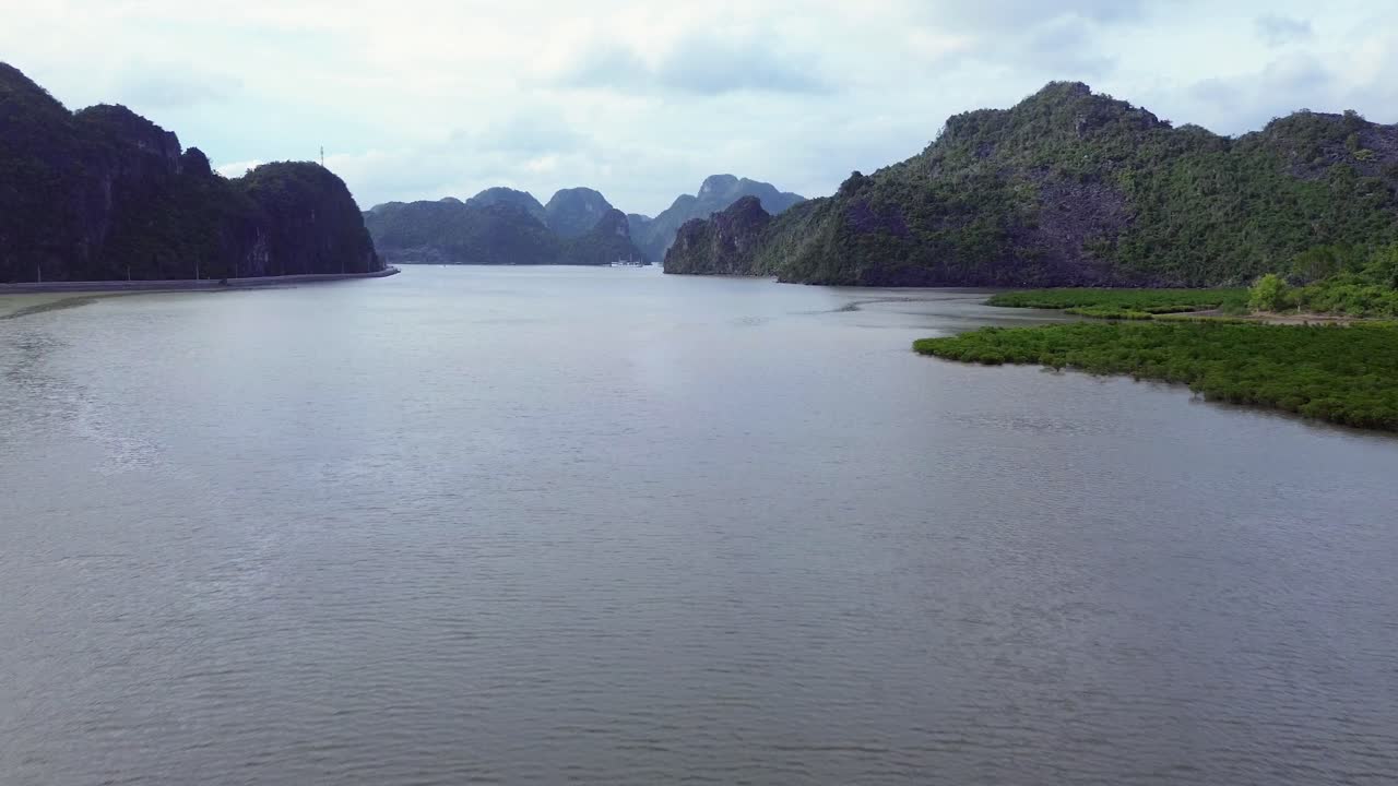 Zoom out of turquoise water and forested rocky islets in Cat Ba Island on a sunny day