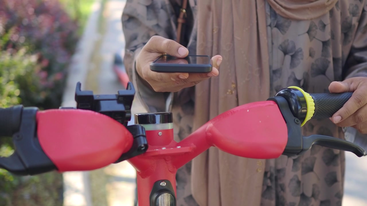 Elektrikli Scooter'ın Kilidini Açmak İçin Akıllı Telefon Kullanan Kişi