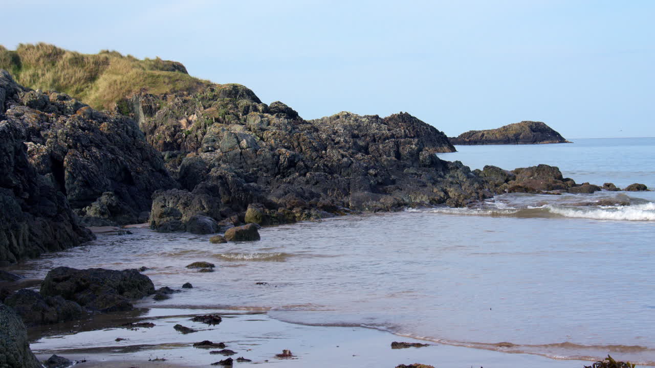Wide Shot of breaking over rocks at Llanddwyn beach and at the Newborough National Nature Reserve