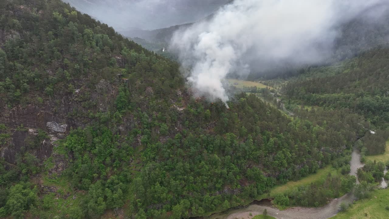 aéreo acercándose a un incendio forestal recién iniciado con humo que se derrama en el vasto paisaje silvestre