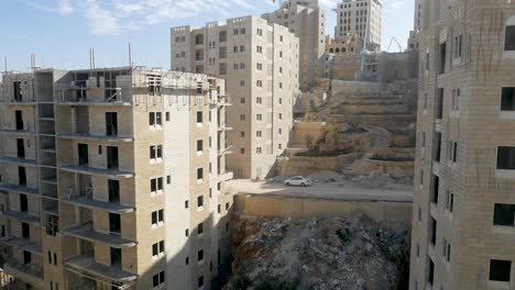 aerial flying between unfinished derelict high-rise buildings on a hillside