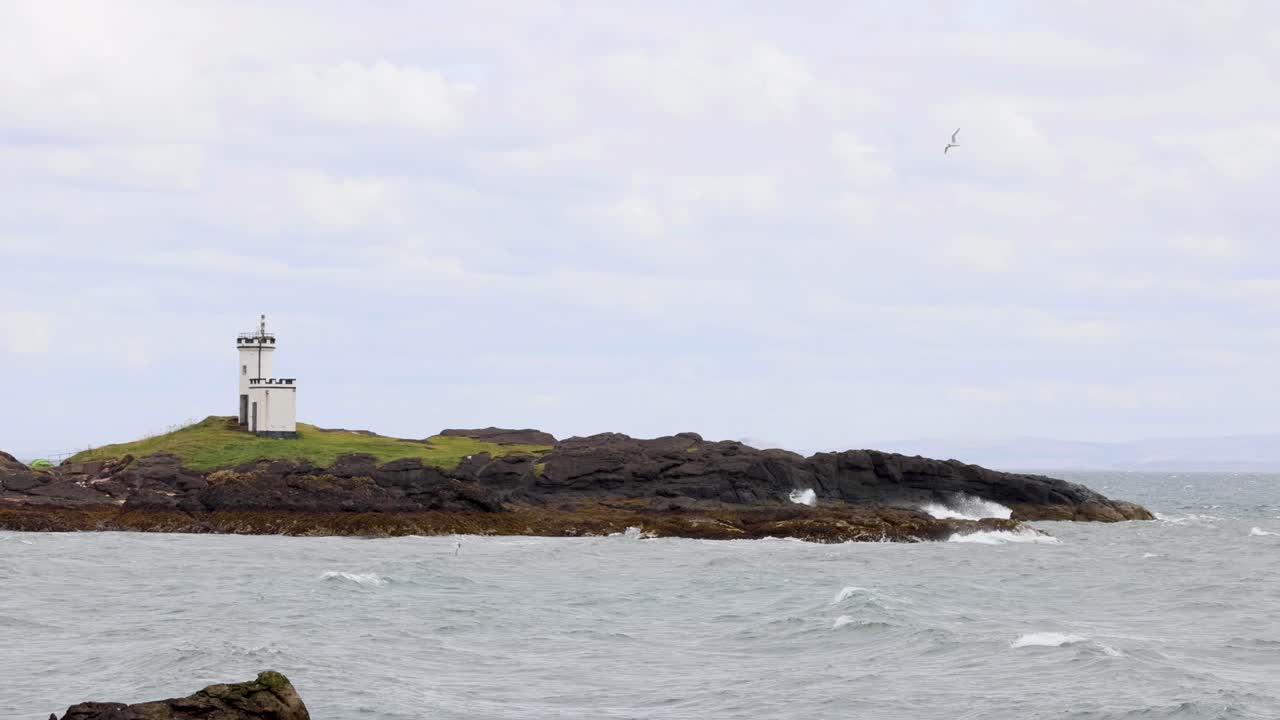 faro en una isla rocosa con olas que se estrellan