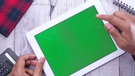 persona usando una tableta con una pantalla verde en un escritorio