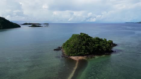 aerial dolly above sandy path at high tide leading to remote tropical island