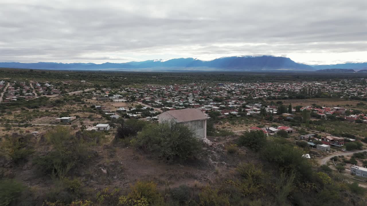 vista aérea de la cima de las colinas con una casa religiosa y el despliegue del valle con casas y más colinas en el horizonte