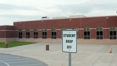 student drop off sign at red brick school building in usa