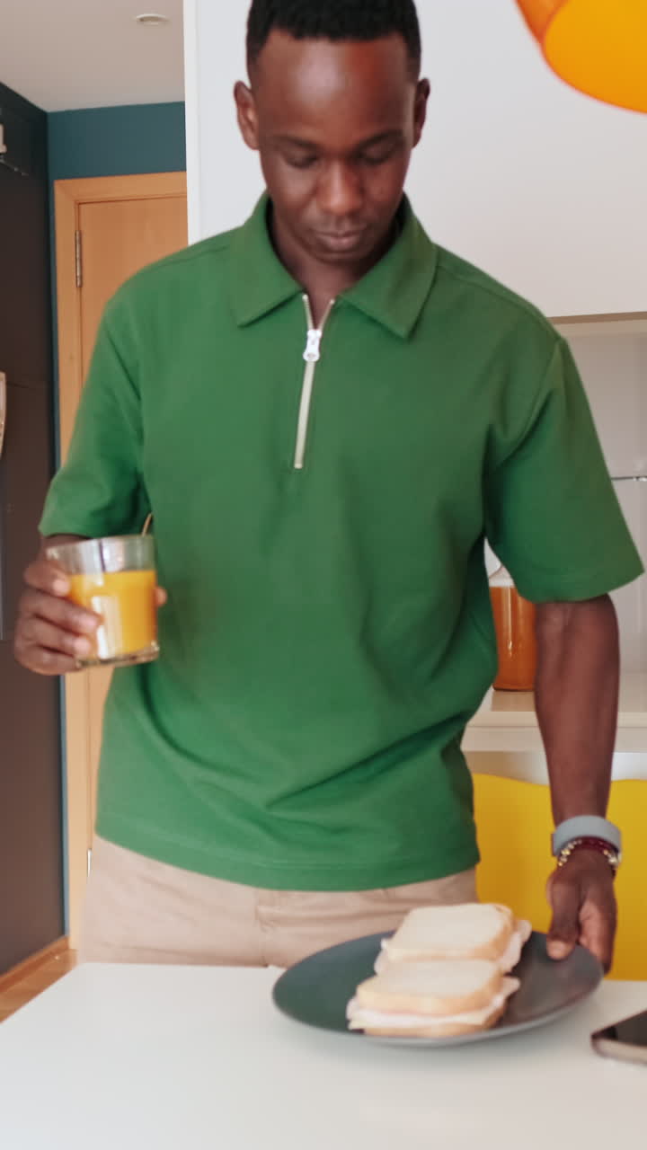Giovane uomo che porta la colazione a tavola in una cucina moderna