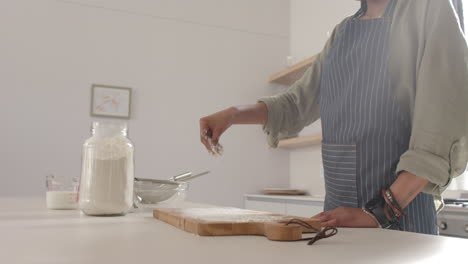 African-American-young-woman-sprinkling-flour-on-board