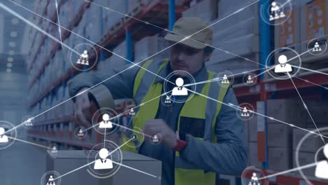 Animation-of-network-of-connections-with-icons-over-caucasian-male-worker-with-cartons-in-warehouse