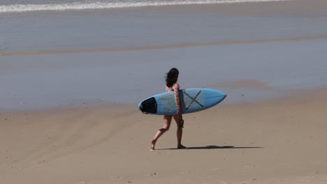 child with surfboard walks towards the ocean