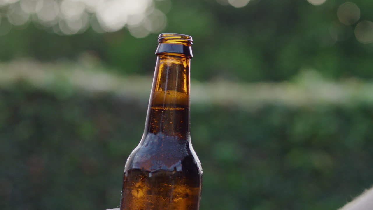 cámara lenta bajando la botella de cerveza abierta marrón