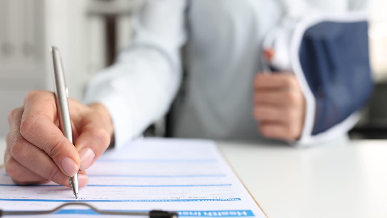 Person with an arm cast filling out a health insurance claim form