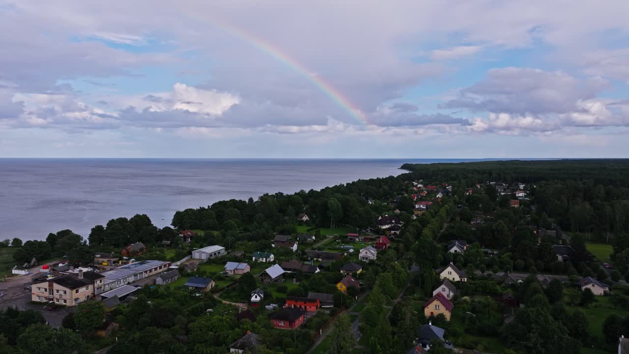 Drone-luftoptagelse over kystbyen Roja i Letland med regnbue over huse ved havet
