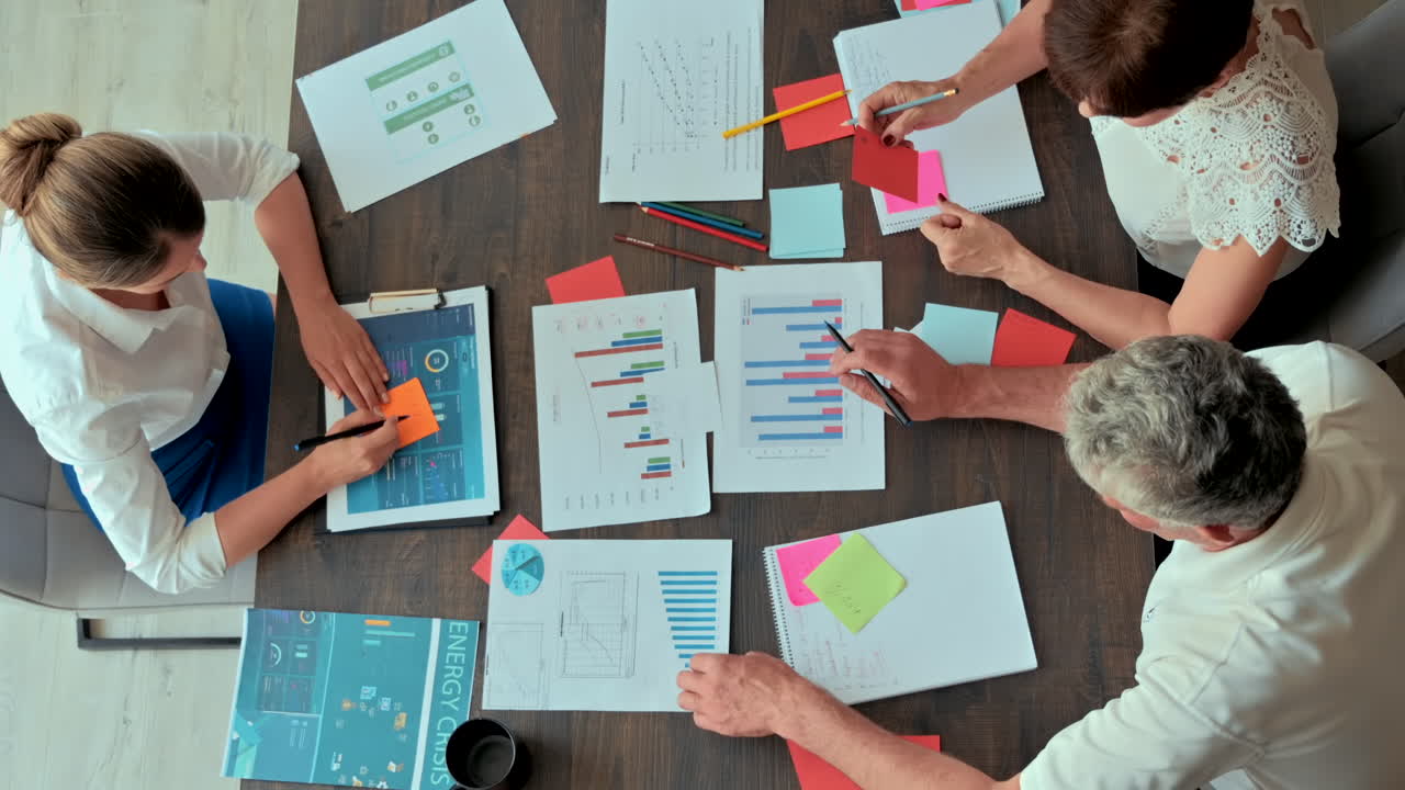 Three coworkers analysing graphs at a desk in an office