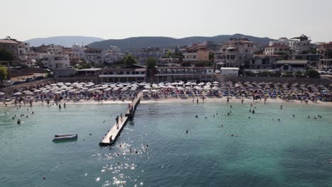 Aerial-flyover-reveals-people-enjoying-the-beach-of-Ksamil,-Albania