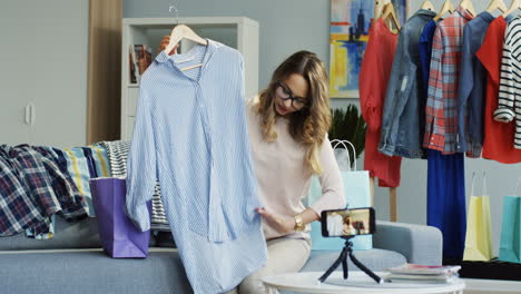 bastante joven bloguera de moda grabando un video y hablando de ropa en casa