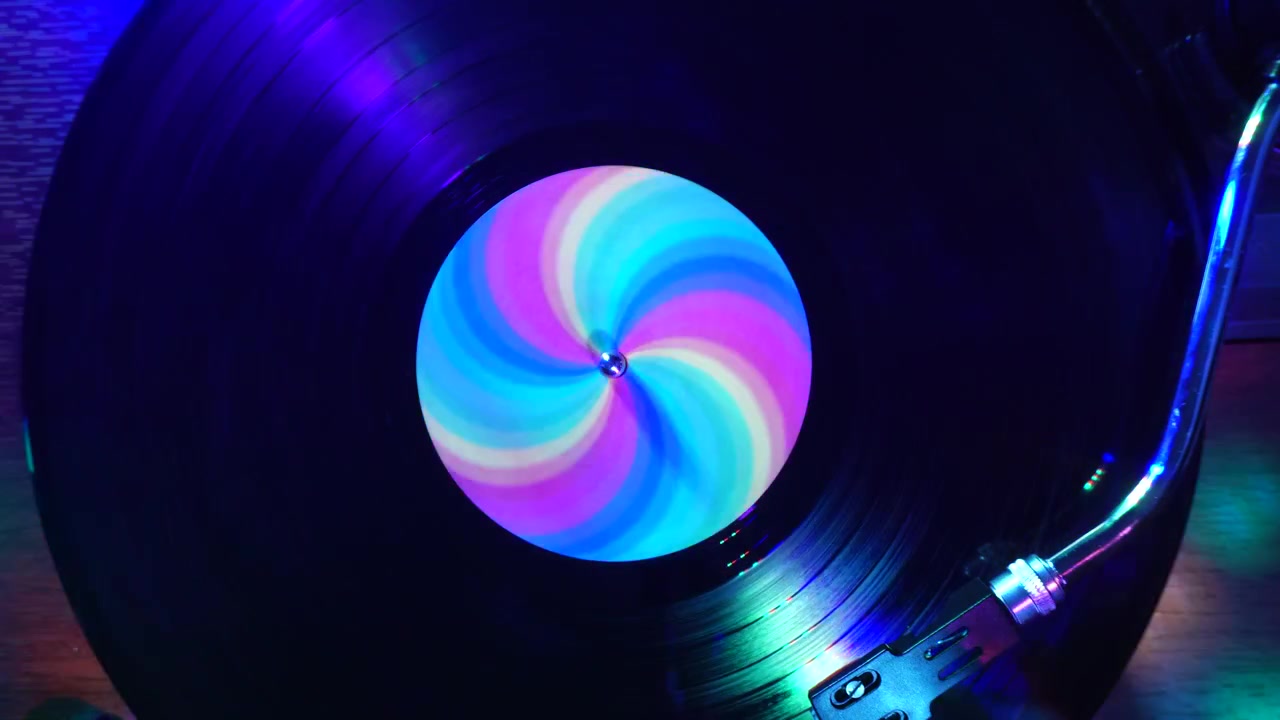 Reproducción de disco de vinilo bajo luces de discoteca de colores, vista cenital