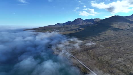 flying over clouds in beautiful eastern fjord of faskrudsfjordur - east iceland ring road