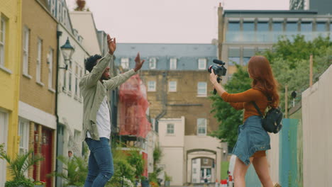 young couple travelling through city together vlogging to video camera on handheld tripod