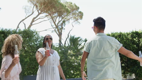 Young-Asian-man-and-biracial-women-enjoy-drinks-outdoors