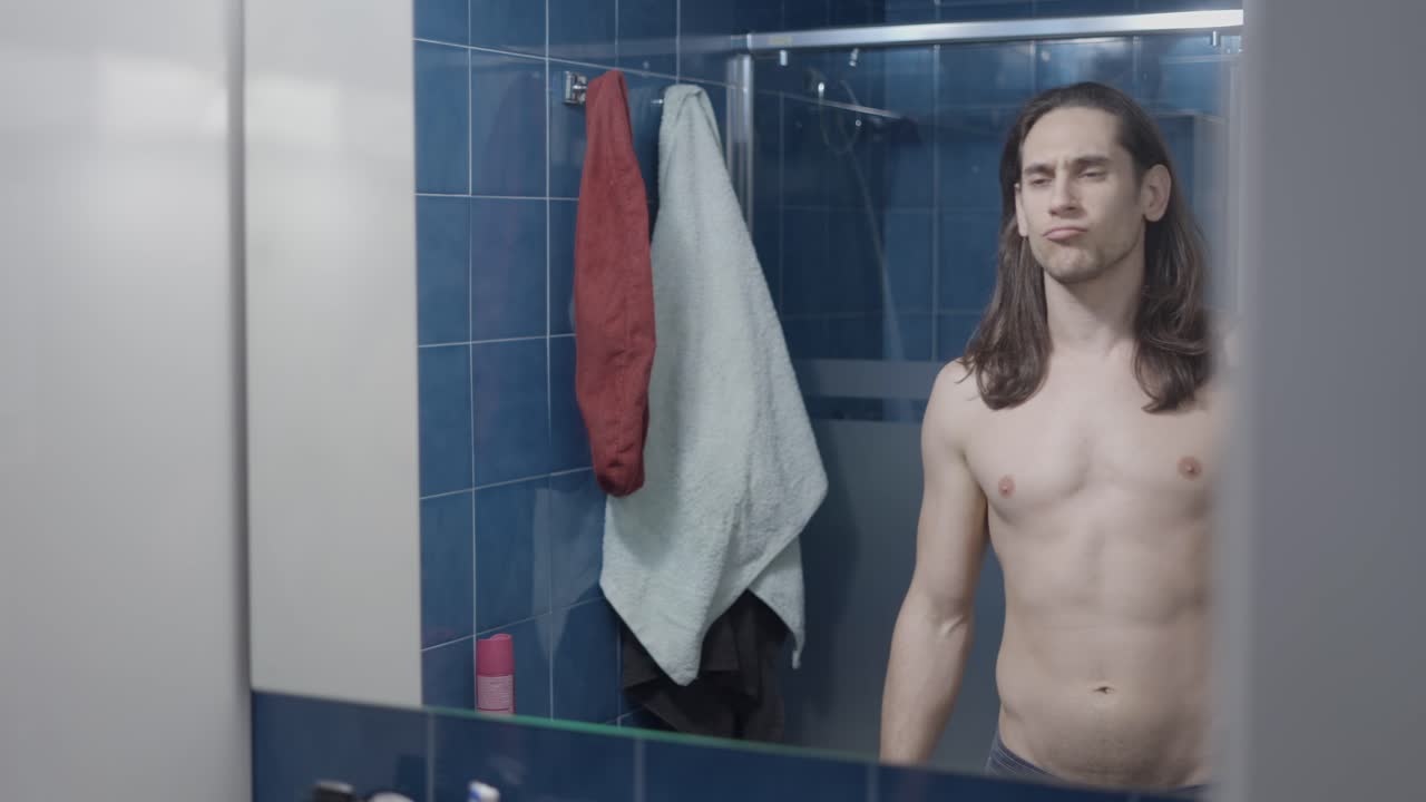 Man checking his physique in bathroom mirror