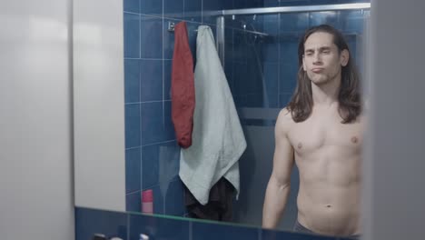 man checking his physique in bathroom mirror