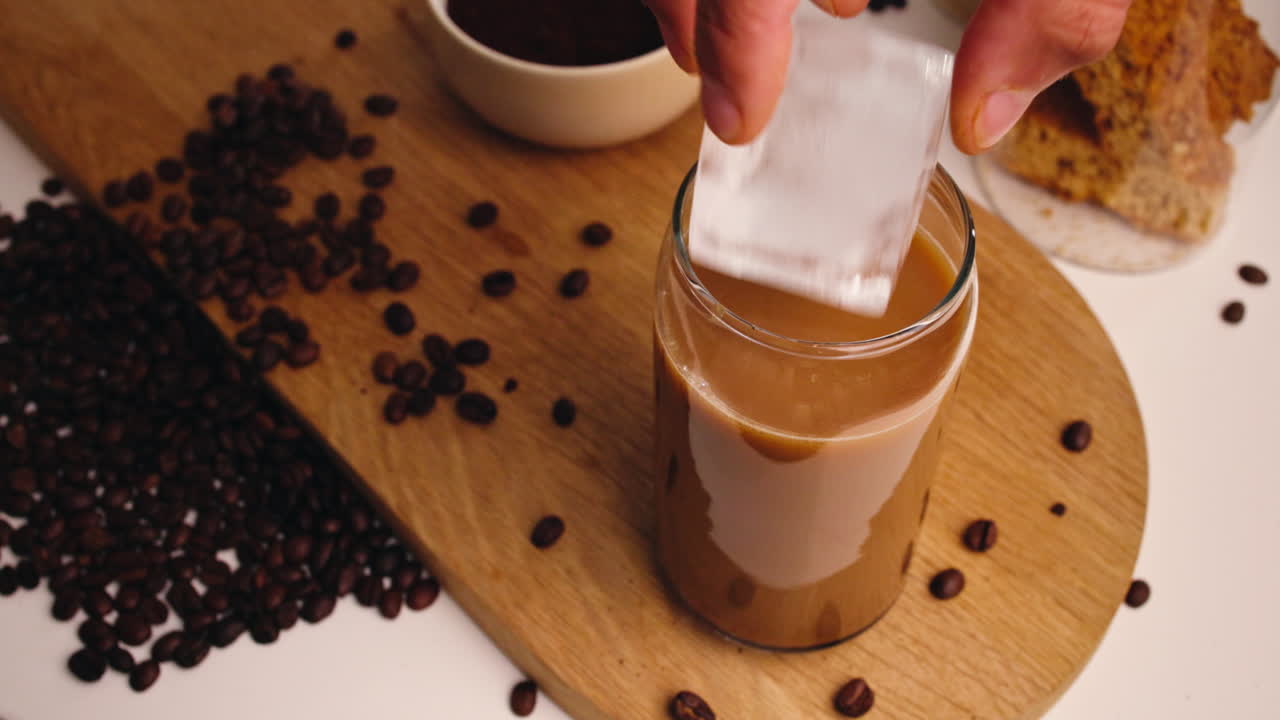 Cubetti di ghiaccio che cadono in un bicchiere di caffè freddo al rallentatore